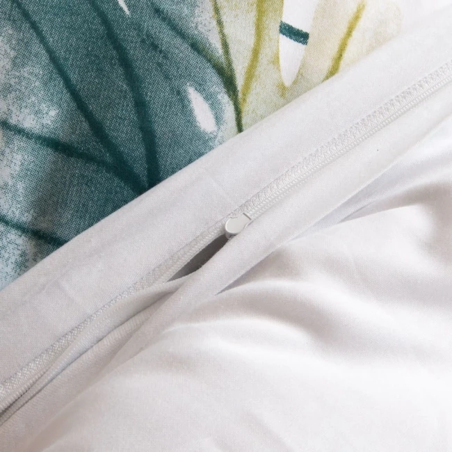 Pościel satyna bawełniana 220x200 cm w kolorze białym z pastelowymi liśćmi. Zamek błyskawiczny na poszewce. Widoczne detale tkaniny oraz wzór liści w odcieniach zieleni i żółci. Pościel z gładką fakturą, idealna do sypialni.