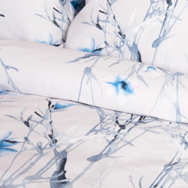 Pościel satyna bawełniana 220x200 w jasnym odcieniu z pastelowymi błękitnymi kwiatkami. Wzór kwiatowy na białym tle, z widocznymi detalami roślinnymi. Położona w złożeniu, z widoczną poszewką na poduszkę i kołdrę.