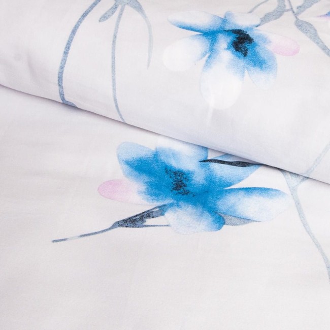 Pościel satyna bawełniana 220x200 w jasnym tle zdobionym pastelowymi, błękitnymi kwiatami. Widziana z góry, złożona w sposób umożliwiający podgląd wzoru i faktury materiału. Brak widocznych napisów czy logo.