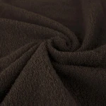 Komplet ręczników z bawełny Solano w eco pudełku, w kolorze ciemnobrązowym. Widoczna struktura materiału, miękka i puszysta. Ręczniki złożone, ukazujące fakturę i jakość bawełny. Idealne do łazienki lub na prezent.