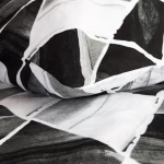 Pościel bawełniana 220x200 Cottonlove w biało-czarne symetryczne romby, leżąca na podłożu, zbliżenie na fakturę materiału. Widoczny wzór rombów, bez napisów.