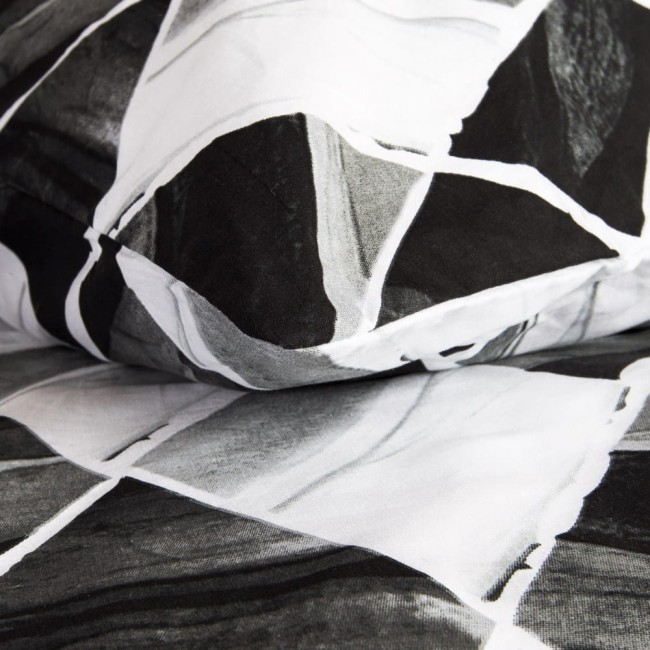 Pościel bawełniana 220x200 Cottonlove w biało-czarne symetryczne romby, leżąca na podłożu, zbliżenie na fakturę materiału. Widoczny wzór rombów, bez napisów.