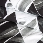 Pościel bawełniana 220x200 w biało-czarny wzór symetrycznych rombów. Złożona, ukazująca detale faktury tkaniny. Tło neutralne, co podkreśla wzór. Przykład nowoczesnego designu do sypialni.