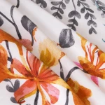 Pościel bawełniana 140x200 Cottonlove w kolorze białym z tropikalnymi pomarańczowymi kwiatami. Widoczny wzór kwiatowy na gładkim tle, pościel złożona w trzech warstwach, ukazująca szczegóły faktury i intensywność kolorów.