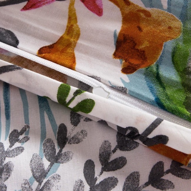 Biała pościel bawełniana 140x200 z kolorowymi tropikalnymi pomarańczowymi kwiatami oraz zielonymi liśćmi. Zamek błyskawiczny na jednym z brzegów. Widok z góry na zgięte lub złożone elementy. Proste tło.