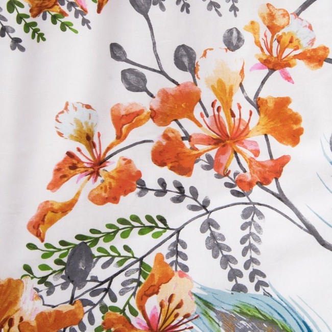 Pościel bawełniana 140x200 Cottonlove w białym kolorze z tropikalnym wzorem w pomarańczowe kwiaty i zielone liście. Materiał gładki, z wyraźnym nadrukiem. Ujęcie z bliska, ukazujące detale wzoru.