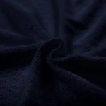 Pościel frotte w kolorze ciemnego granatu, wykonana z miękkiego materiału, leżąca w złożeniu. Widoczna struktura frotte, delikatnie teksturowana, bez dodatkowych wzorów czy napisów. Idealna do użytku na łóżku o wymiarach 200x220 cm.