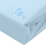 Ochronne prześcieradło z gumką 140x200 w kolorze błękitnym, leżące na gładkiej powierzchni. Materiał ma subtelną fakturę i jest częściowo zwinięty. Widoczne krople wody na tkaninie podkreślają właściwości wodoodporne.