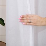 Firana gotowa w kolorze białym na srebrnych przelotkach, wisząca, z gładkiej, lekko przezroczystej tkaniny. Zdjęcie przedstawia zbliżenie na tkaninę oraz rękę z różowymi paznokciami trzymającą firanę. Tło jest delikatne i jasne.