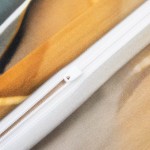 Zbliżenie na zamek błyskawiczny pościeli satynowej w kolorze złotym i turkusowym. Widoczne części materiału z delikatnym połyskiem, z białym zamkiem. Pościel w układzie leżącym, co pozwala na ocenę tekstury tkaniny.