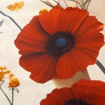 Pościel satynowa w kolorze kremowym z dużymi, czerwonymi kwiatami można w zbliżeniu zobaczyć. Wzór ukazuje detale płatków kwiatów oraz subtelne akcenty żółtych elementów. Materiał ma gładką, lśniącą fakturę.