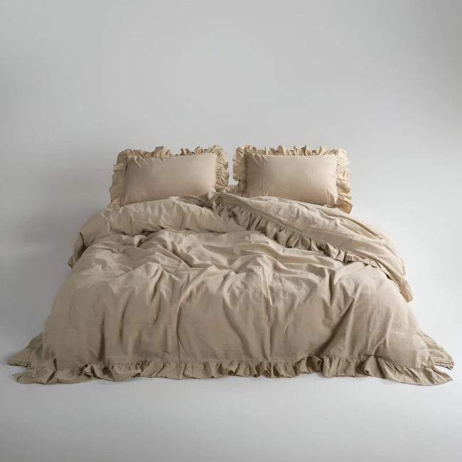 Pościel bawełniana z falbanką w kolorze beżowym, rozmiar 220x200 cm. Złożona, z poduszkami z falbaniastymi brzegami. Ukazana w ujęciu frontalnym na jasnym tle, podkreślająca teksturę materiału i detale wykończenia.