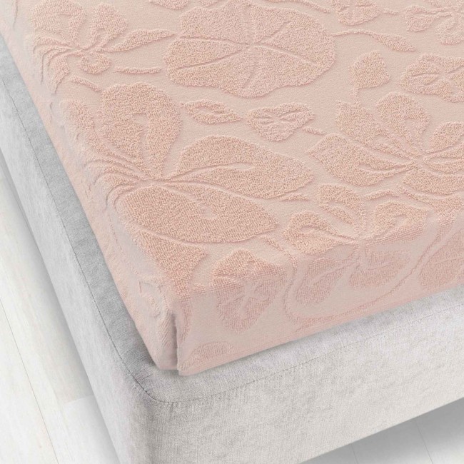 Prześcieradło żakardowe w kolorze jasnego różowego, o wymiarach 150x205 cm, z wysuniętym wzorem roślinnym. Produkt leżący na łóżku, dobrze widoczna struktura tkaniny. Brak gumki, idealne do klasycznego użytku. Tło jasne, proste, podkreślające materiał.