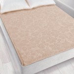 Prześcieradło żakardowe bez gumki o wymiarach 150x205 cm w jasnym beżowym kolorze, leżące na łóżku. Materiał ma delikatny, teksturowany wzór roślinny. Tło neutralne, podkreślające kolor i fakturę produktu. Widoczne poduszki w białych poszewkach.