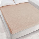 Prześcieradło żakardowe bez gumki w kolorze jasnego beżu, o wymiarach 175x220 cm, ułożone na łóżku. Wzór z wysublimowanymi detalami roślinnymi, lekko teksturowana powierzchnia. W tle widoczne jasne poduszki oraz łóżko o szarym kolorze.