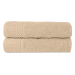 Zestaw dwóch ręczników z bawełny w kolorze jasnobeżowym, leżących na sobie. Ręczniki mają teksturę frotte oraz dekoracyjny wzór w formie rombów na górze. Wymiary i marka nie są widoczne.