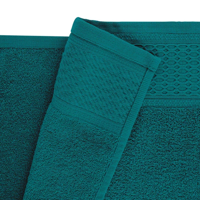 Komplet ręczników z bawełny Solano w kolorze głębokiego błękitu, z gładką i teksturowaną strukturą. Widoczne detale, takie jak delikatny wzór w sześciokąty na brzegu oraz staranne wykończenie. Ręczniki leżą płasko, ukazując różnorodność faktur.