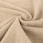 Komplet ręczników z bawełny w kolorze beżowym, z bliska ukazujący teksturę materiału. Ręczniki leżą na płaskiej powierzchni, z lekko zwiniętym brzegiem. Produkt w eco pudełku, doskonały do użytku domowego lub jako prezent.