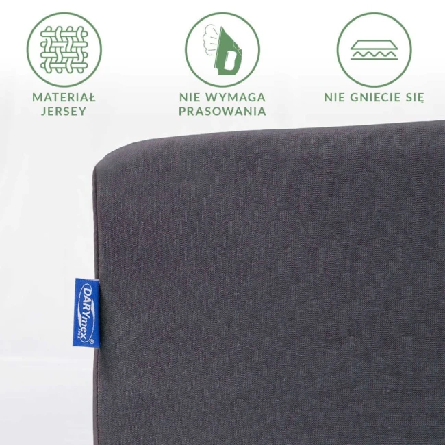 Prześcieradło jersey z gumką 160x200 w ciemnoszarym kolorze, rozłożone na płaskiej powierzchni. Widać teksturę materiału oraz metkę z logo. Na górze zdjęcia ikonki informujące o właściwościach: nie wymaga prasowania i nie gniecie się.