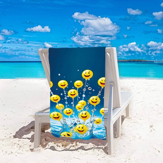 Ręcznik plażowy 100x180 cm w kolorze niebieskim z wzorem żółtych buziek, wykonany z szybkoschnącej mikrofibry. Leży na leżaku na plaży, w tle woda i błękitne niebo. Produkt rozłożony, zapewnia wygodę przy odpoczynku na plaży.