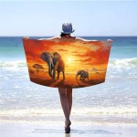 Ręcznik plażowy 100x180 cm z mikrofibry, z grafiką słoni na safari w odcieniach pomarańczowych i żółtych, rozłożony za osobą stojącą na plaży. Produkt szybkoschnący, widoczny w kontekście plażowym, tło z niebieskim morzem i jasnym niebem.