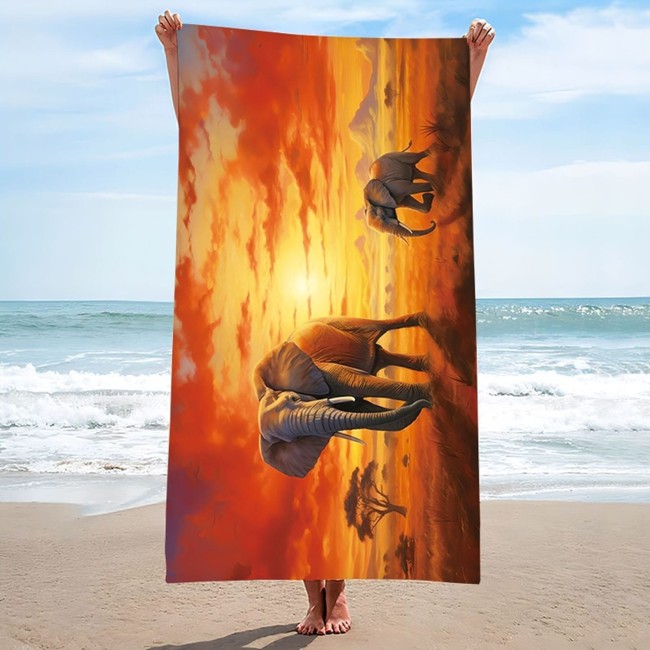 Ręcznik plażowy 100x180 z mikrofibry z wzorem słoni na safari, w kolorach pomarańczowym i brązowym, trzymany w pozycji pionowej. Na tle plaży i morza, w zbliżeniu na detale wzoru zwierząt w kontrastującym otoczeniu zachodu słońca.