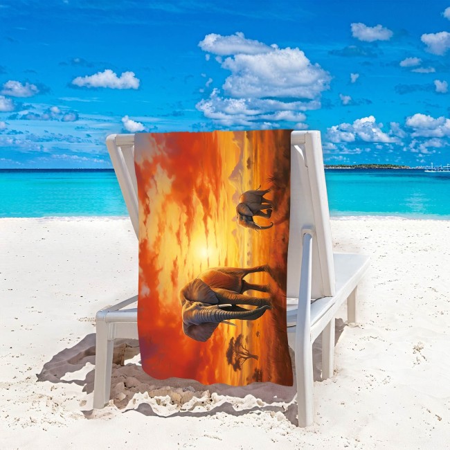 Ręcznik plażowy 100x180 cm z mikrofibry z motywem słoni na tle zachodzącego słońca. Produkt leży na leżaku, w ujęciu z boku.