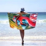 Ręcznik plażowy 100x180 cm z kolorowym wzorem flaminga w okularach, wykonany z mikrofibry. Złożony w dłoniach osoby stojącej na plaży, z widocznym tłem morza i nieba. Szybkoschnący, duży i różowy, idealny na lato.