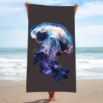 Ręcznik plażowy 100x180 cm, wykonany z mikrofibry, z grafiką przedstawiającą meduzę w kolorze niebiesko-fioletowym na ciemnym tle. Produkt trzymany w pionie, z plażą i morzem w tle, idealny do użytku w sezonie letnim.