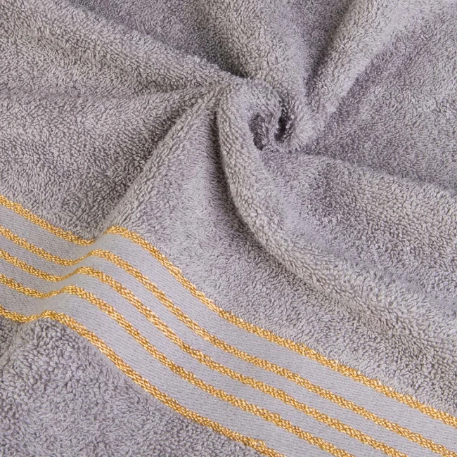 Ręcznik do rąk 30x50 cm w kolorze szarym, wykonany z bawełny o gramaturze 500 g/m². Na dolnej krawędzi widoczne bordiury z złotymi paskami. Ułożony w złożony sposób, ukazujący fakturę materiału i detale dekoracyjne.