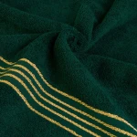 Ręcznik kąpielowy 50x90 cm w kolorze zieleni butelkowej z bordiurą w złote paski. Złożony, widoczna faktura materiału bawełnianego o gramaturze 500 g/m2, w zbliżeniu na wzór. Brak dodatkowych akcesoriów i napisów.