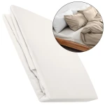 Prześcieradło flanelowe z gumką w kolorze kremowym, rozmiar 200x220 cm, leży na białym tle. Produkt jest złożony, ukazuje gładką, teksturowaną powierzchnię materiału. W tle widoczna aranżacja sypialni z poduszkami i pościelą w odcieniach beżu.