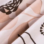 Pościel bawełniana w rozmiarze 140x200 w beżowe kwiaty, wykonana z miękkiego materiału. Kąt ujęcia zbliżony na detale, pokazujący wzór oraz delikatne faktury tkaniny. Tło jasne, co eksponuje kolory i motywy.