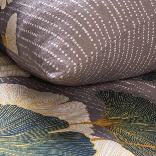 Pościel flanelowa 180x200 cm w kolorze ciemnoszarym, z wzorem liści miłorzębu w odcieniach zieleni i żółci. Ułożona na tle, zbliżenie na detal, poduszka wyraźnie wyeksponowana z białymi kropkami na materiale. Tekstura flaneli, matowe wykończenie.