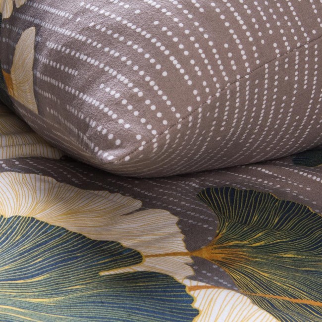 Pościel flanelowa 220x200 Solenne Dark szara z liśćmi miłorzębu, w złożeniu, ukazuje poduszkę i część narzuty. Materiał ma teksturę flanelową w szarym odcieniu z białymi kropkami oraz delikatnymi wzorami liści w zieleni i żółci na tle.