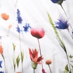 Pościel flanelowa 180x200 Florina Snow w białym kolorze z nadrukiem kolorowych kwiatów, widok w zbliżeniu na detal wzoru. Kwiaty w odcieniach czerwieni, niebieskiego i zieleni na jasnym tle. Ułożona płasko, eksponująca teksturę materiału.