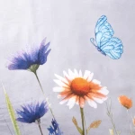 Pościel flanelowa 160x200 Florina Mist w odcieniu szaro-niebieskim z kolorowymi kwiatami oraz niebieskim motylem. Wzór floralny na miękkiej fakturze materiału. Produkt leży na równym tle, prezentując detal zbliżenia na kwiaty i motyla.