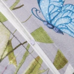 Zbliżenie na zamknięcie białego zamka błyskawicznego pościeli flanelowej Florina Mist w odcieniach szarości, z kolorowymi wzorami kwiatów i niebieskimi motylami. Widoczne detale tekstury materiału flanelowego oraz liściowego wzoru.
