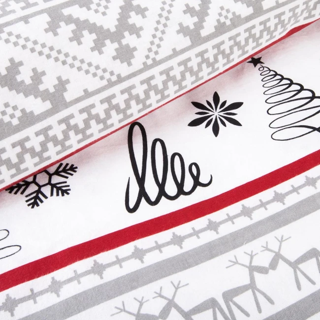 Pościel flanelowa 140x200 cm w kolorze białym, ozdobiona wzorami choinek oraz chatkami w odcieniach szarości i czerwieni. Produkt leży na płaskiej powierzchni, pokazując detale wzorów i fakturę materiału flanelowego.