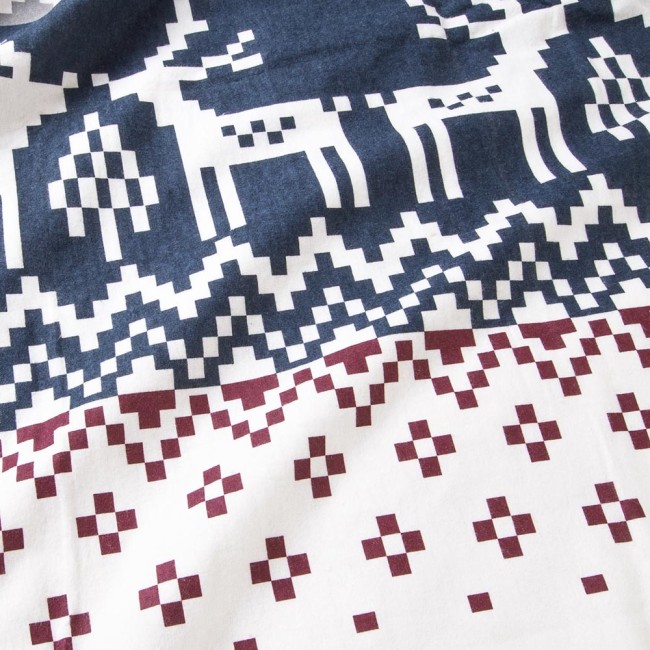 Pościel flanelowa 160x200 Arvena w bordowe renifery i biało-niebieską kratkę. Wzór składa się z reniferów oraz geometrycznych elementów. Tkanina jest miękka i teksturowana, w układzie leżącym na jasnym tle.