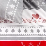 Pościel flanelowa 160x200 w odcieniach szarości, z wzorami w serca i choinki. Poduszka leży na rozłożonej narzucie. Tło jasne, jednolite. Materiał teksturowany, miękki w dotyku. Widoczne są dekoracyjne detale w kolorze czerwonym oraz szarym.