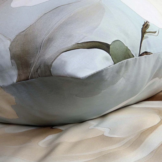 Pościel satyna bawełniana 220x200 Riviera w szaro-kremowe róże, widoczna z boku. Złożona na łóżku z delikatnymi, pastelowymi odcieniami. Wzór kwiatowy na poduszkach kontrastuje z gładkim tłem, materiał gładki i błyszczący, podkreślający elegancję.