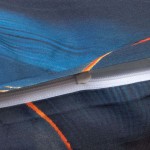 Zbliżenie na zamek błyskawiczny pościeli satyna bawełniana w kolorze niebieskim z motywem złotych kwiatów, ukazujące teksturę materiału oraz detal szycia. Pościel rozłożona, widać kontrastujące elementy wzoru.