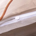 Zbliżenie na zamek błyskawiczny pościeli satynowej w kolorze jasnego beżu z kremowym tłem, z delikatnym wzorem w odcieniach brązu. Widoczna faktura materiału oraz sposób wykończenia zamka.