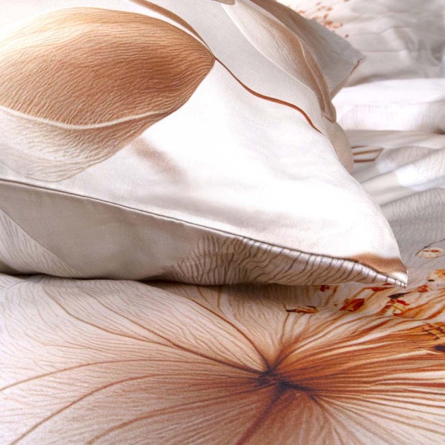 Pościel satyna bawełniana 220x200 Elize w jasnym beżowym kolorze z wzorem kwiatowym na kremowym tle, z poduszką o zaokrąglonym kształcie. Ułożona w zbliżeniu, ukazuje połysk materiału oraz detale kwiatowych zdobień.