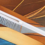 Zbliżenie na fragment pościeli satynowej bawełnianej Aurelia 140x200, ukazujący zamek błyskawiczny na kolorowym tle. Wzory złotych i niebieskich liści na brązowym oraz szarym tle, wykończenie w odcieniach złota. Tekstura gładka i lśniąca.