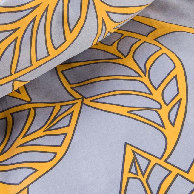 Pościel satyna bawełniana 160x200 z pomarańczowymi liśćmi na szarym tle, w ułożeniu rozłożonym. Wzór liści jest wyraźny, a tło gładkie, co podkreśla kolory. Materiał ma subtelną fakturę, idealny dla komfortowego snu.