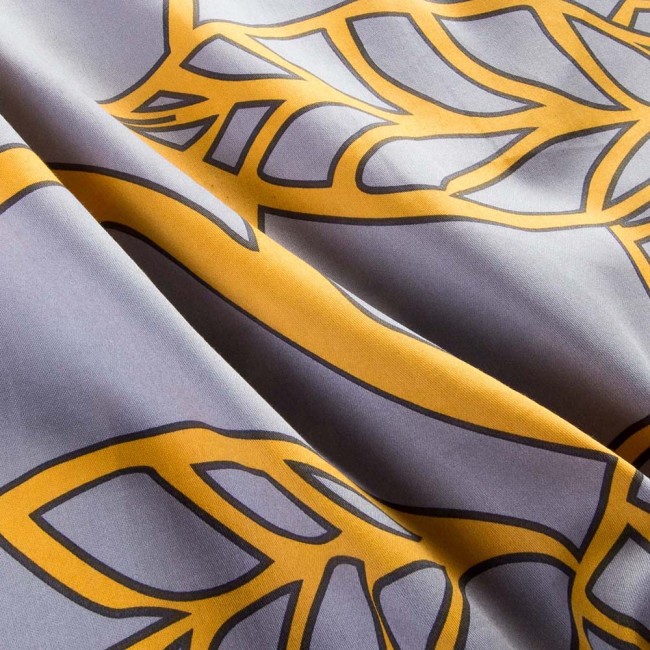 Pościel satyna bawełniana 220x200 Folina w pomarańczowe liście na szarym tle, ukazana z bliska. Wzór z liśćmi w intensywnym odcieniu pomarańczowym na matowej, szarej tkaninie. Widoczna gładka faktura materiału.