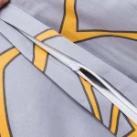 Zbliżenie na zamek błyskawiczny na poszewce pościeli satynowej w kolorze szarym z pomarańczowymi liśćmi. Widoczne detale ukazują jakość wykończenia oraz wzór, który może uzupełnić nowoczesne aranżacje sypialni.