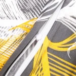 Zbliżenie na zamek błyskawiczny pościeli satynowej w rozmiarze 180x200 cm z białymi i złotymi piórami na szarym tle. Widoczna faktura materiału oraz żółte detale na tle szaro-białym. Zamek w kolorze białym, umieszczony na krawędzi poduszki.